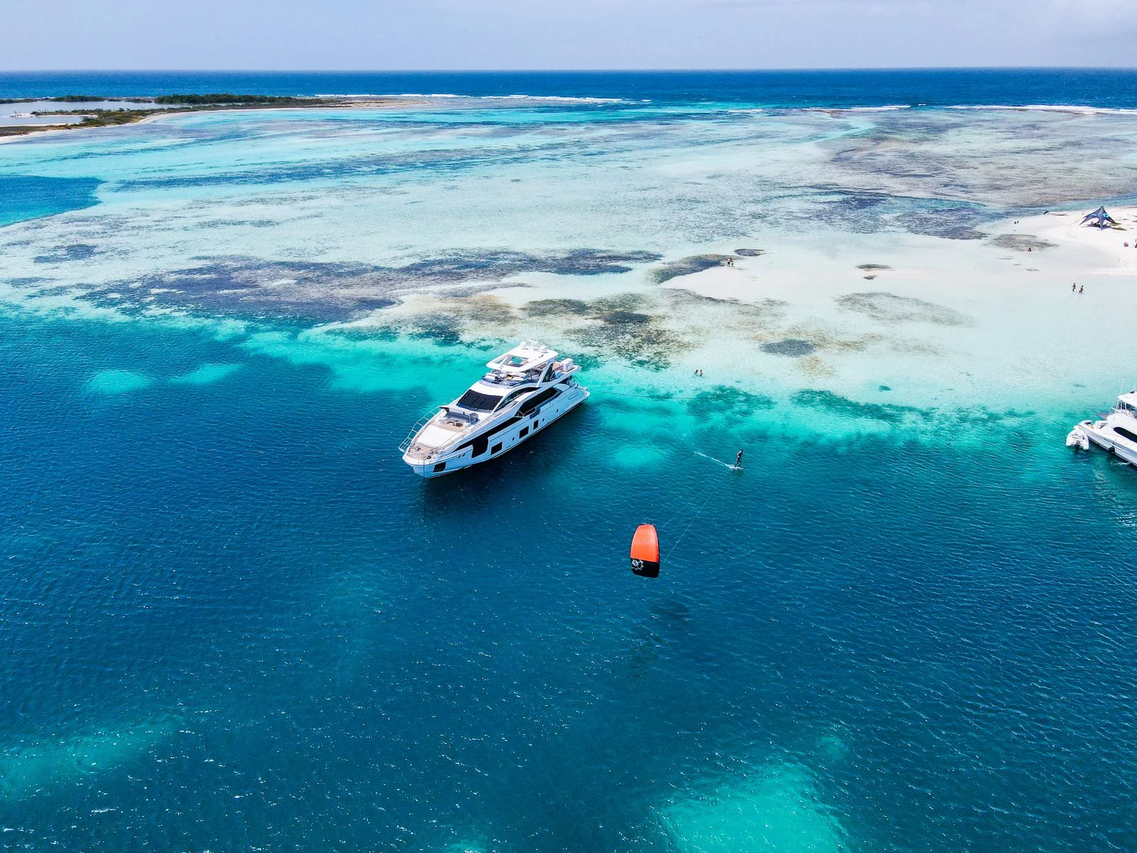 A yacht and kitesurfer in brilliant turquoise lagoon water